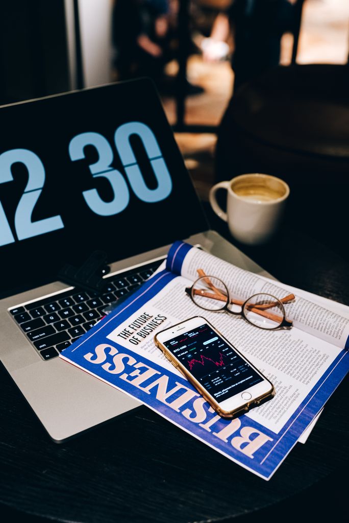 A modern workspace featuring a laptop, smartphone, and coffee for business and finance tasks.