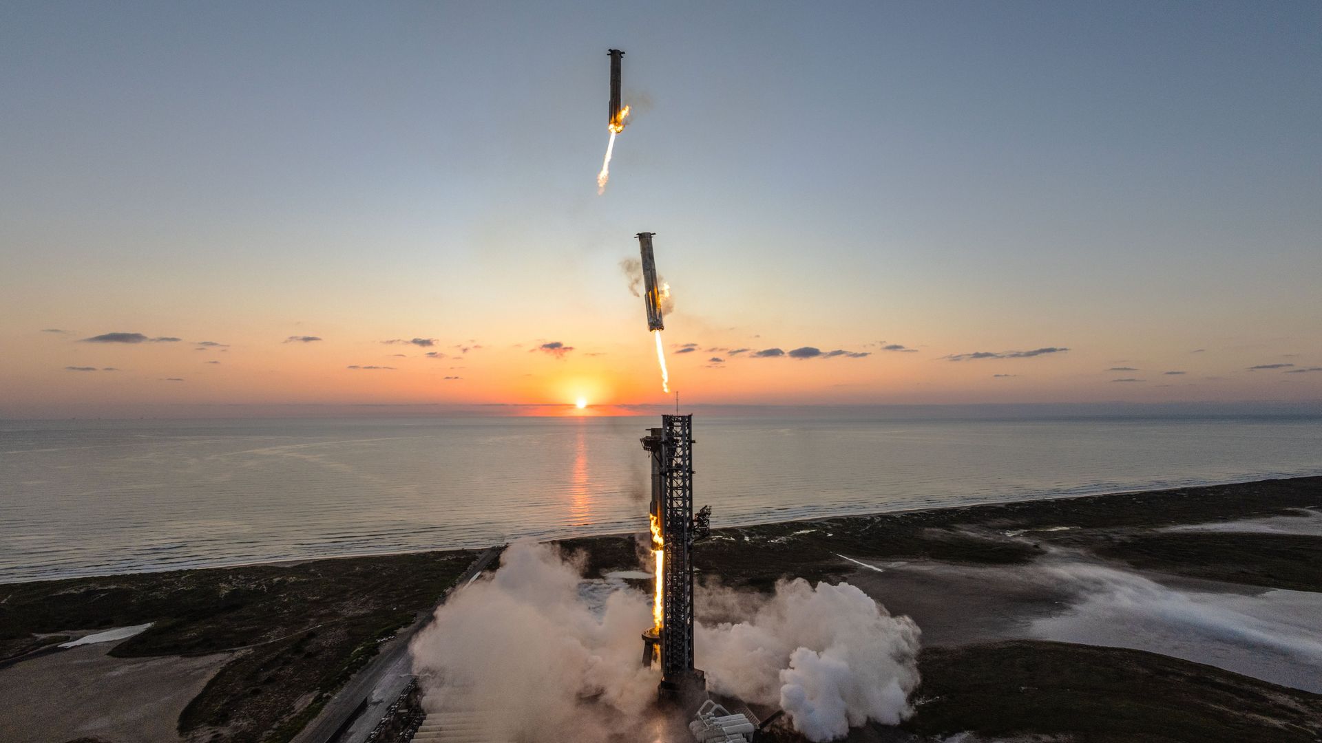 photo showing a big silver rocket coming in for a landing at its seaside launch pad