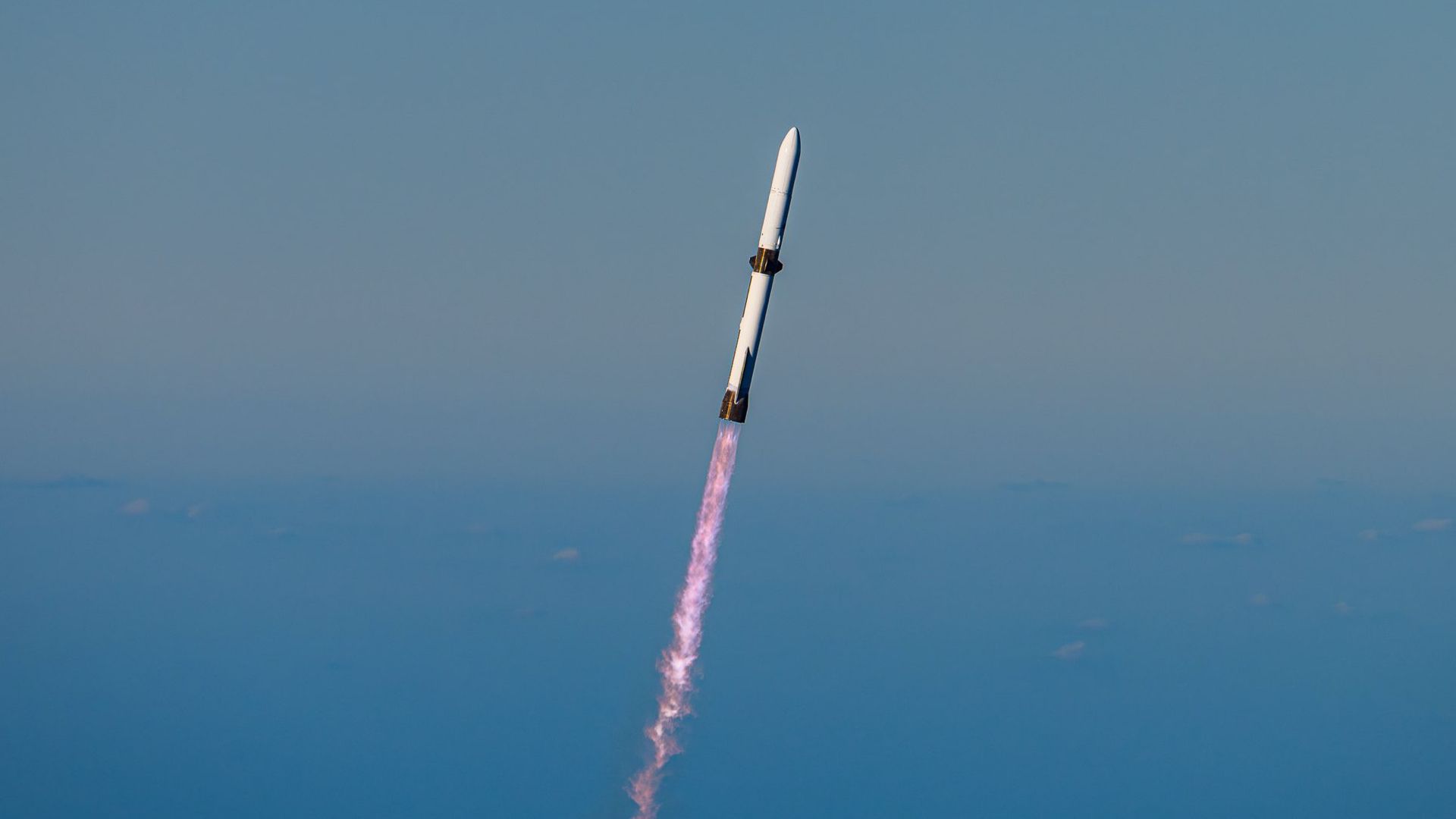 a large white rocket flies through a blue sky