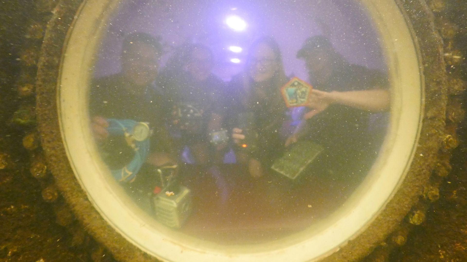 photo of three women and one man, seen fuzzily through a circular porthole