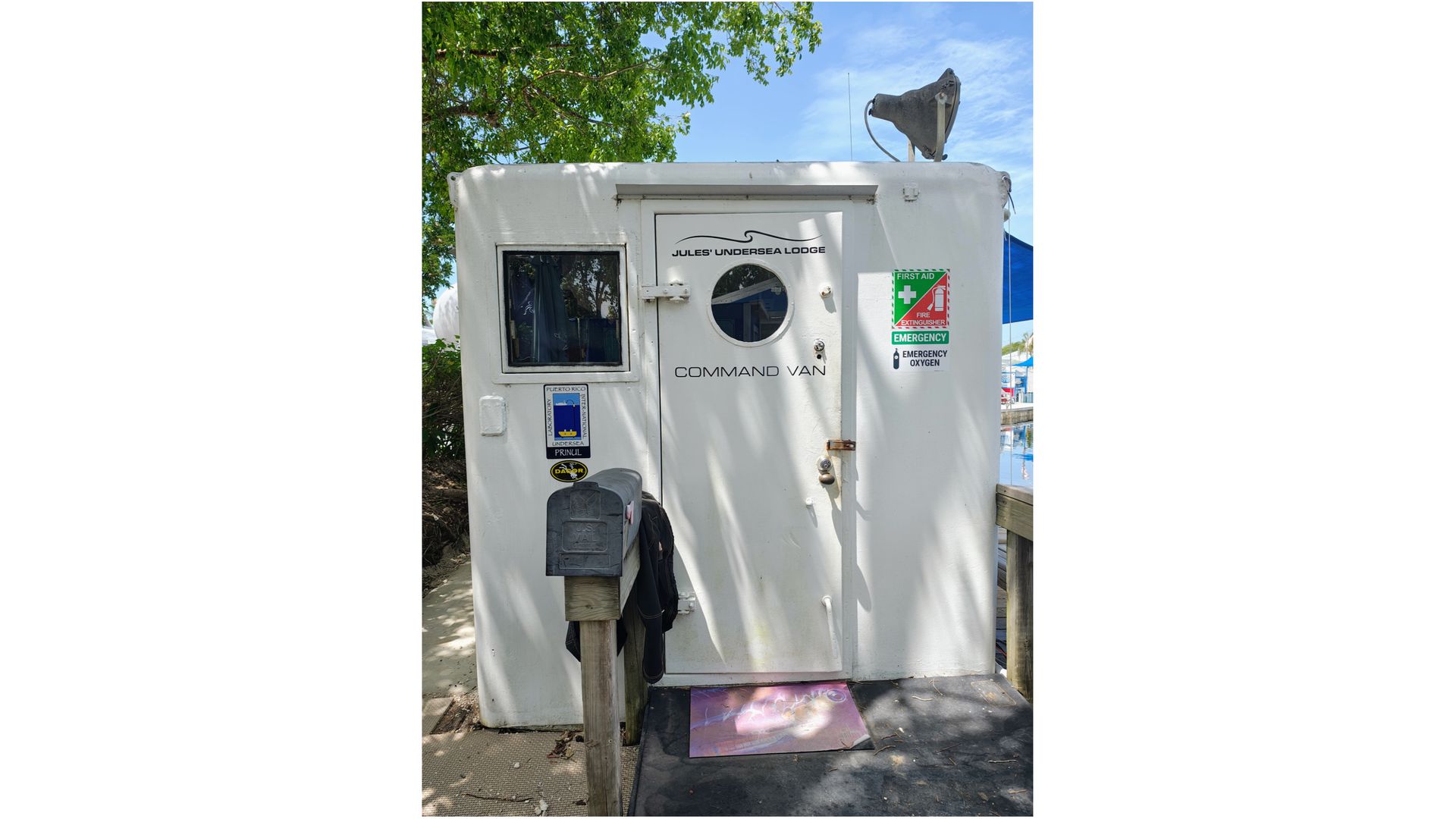 photo of a small white boxy building whose door reads 