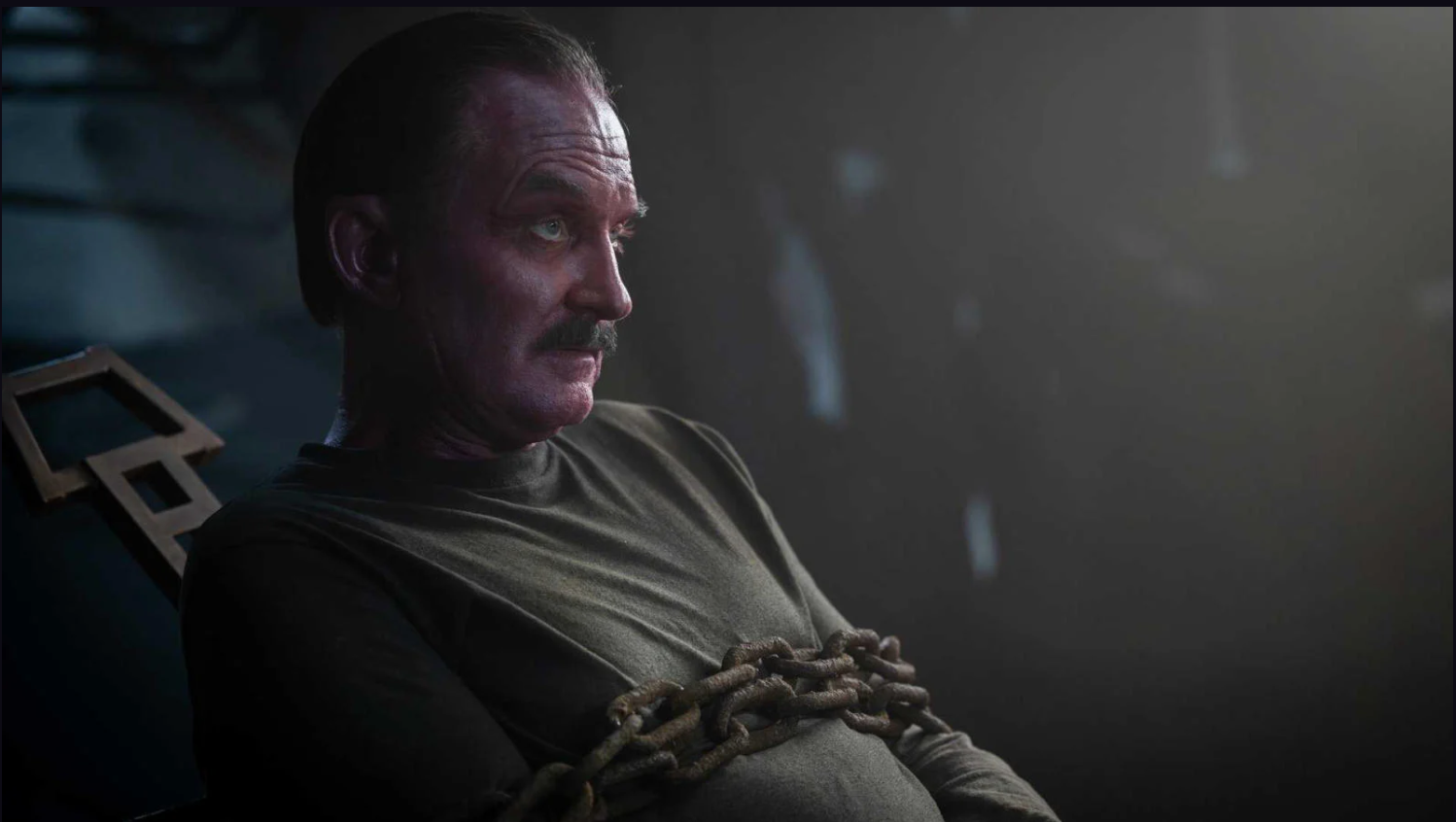 a red-skinned man chained to a chair