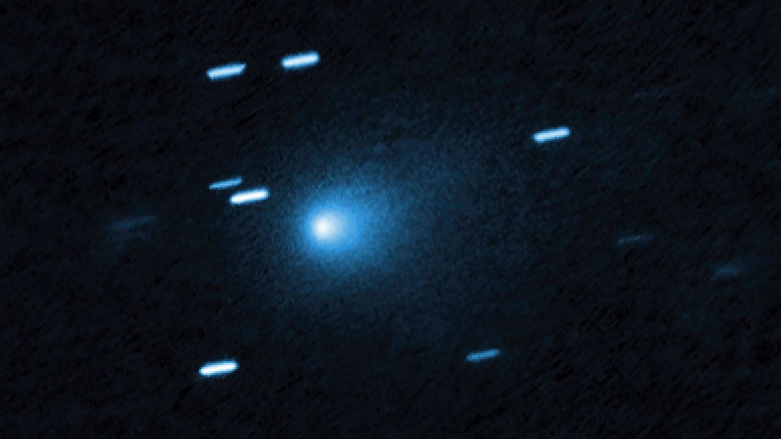 A blue ball of light shines between streaks of blueish light from stars in outer space