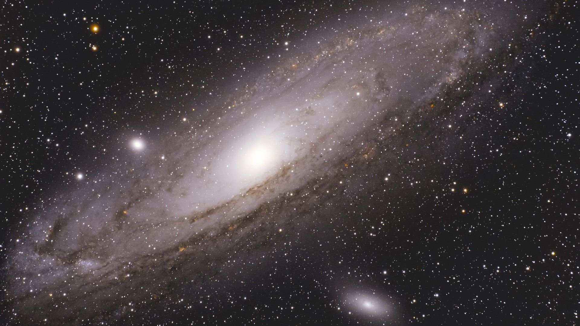 Centered amongst a field of stars is the Andromeda Galaxy which is a massive, brilliant, glowing white core that fades into expansive, oval-shaped spiral arms.