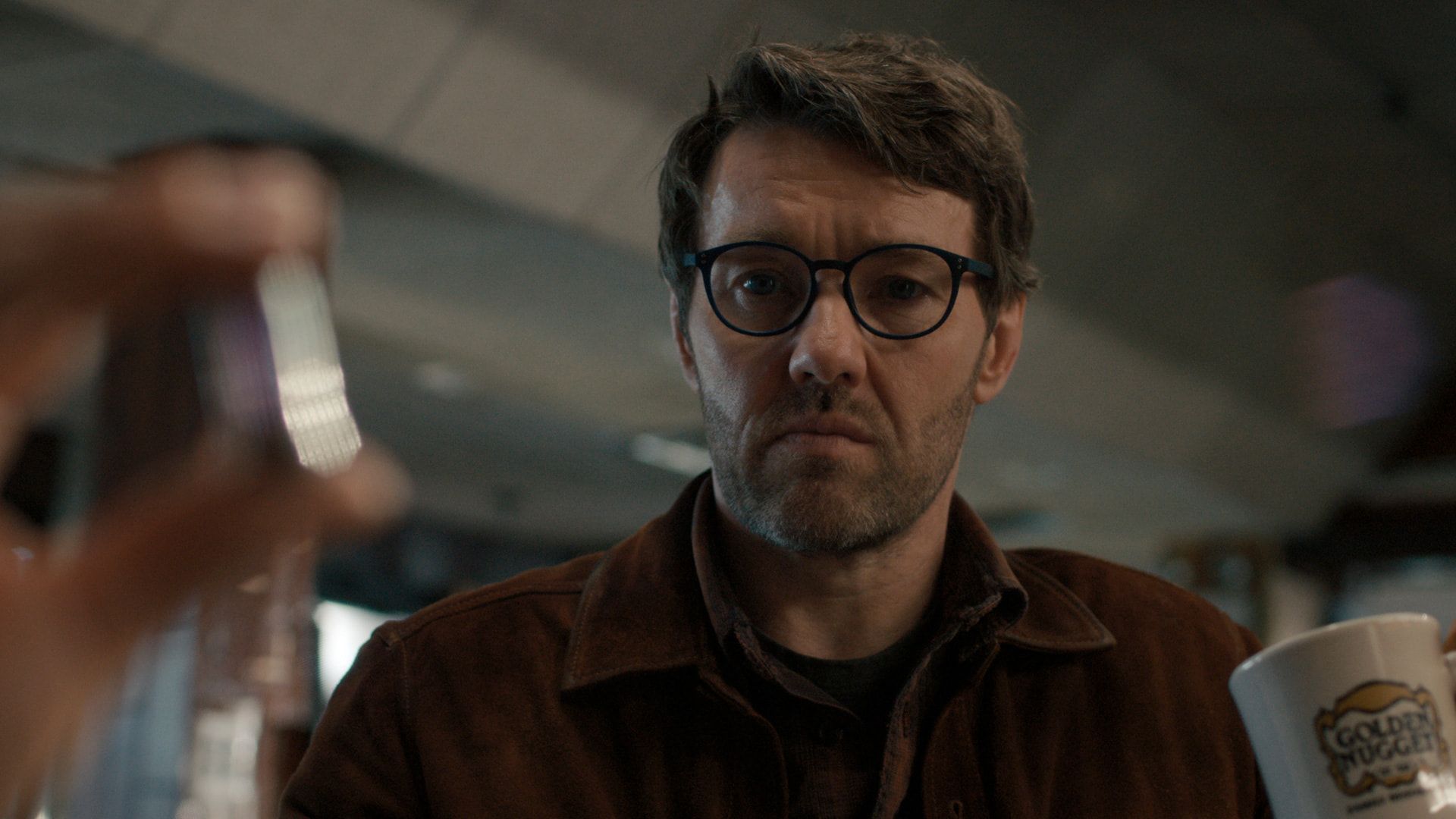 a bearded man with glasses stares intently