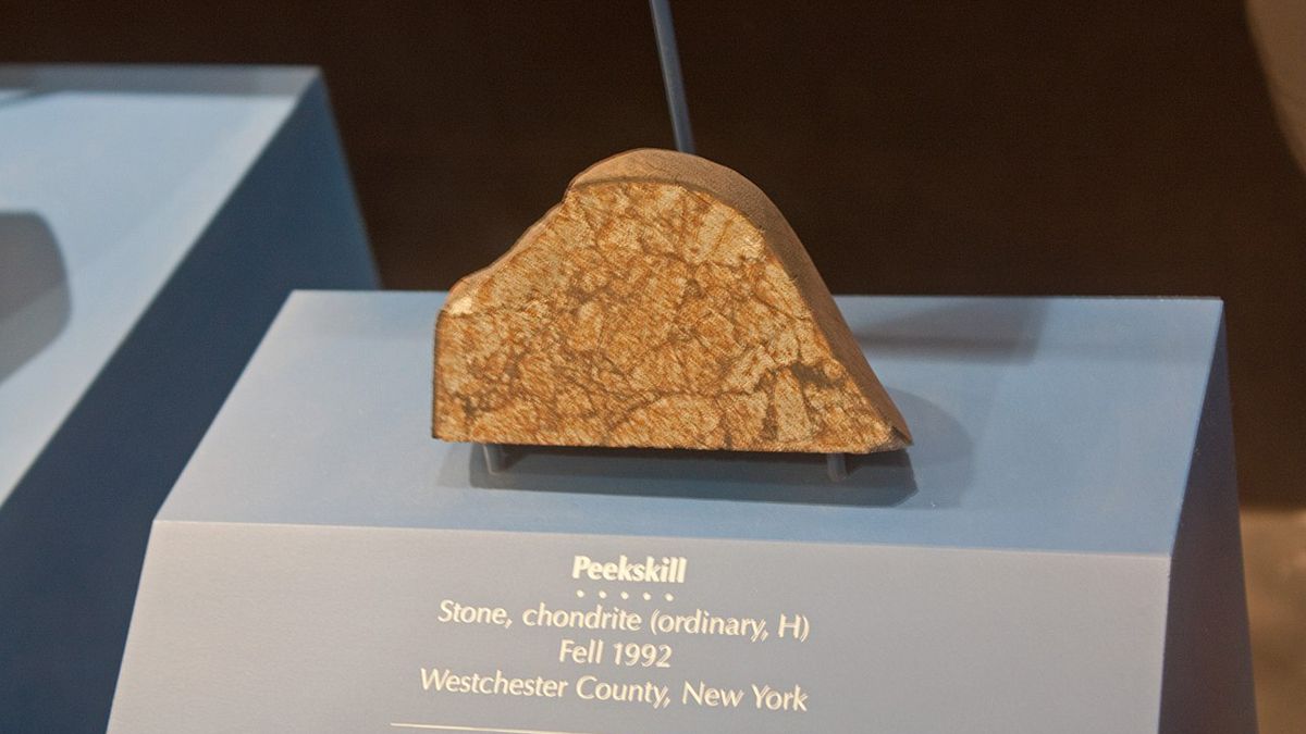 an orange and brown-striped chunk of rock with a smooth, rounded top edge and a flat cross-section face