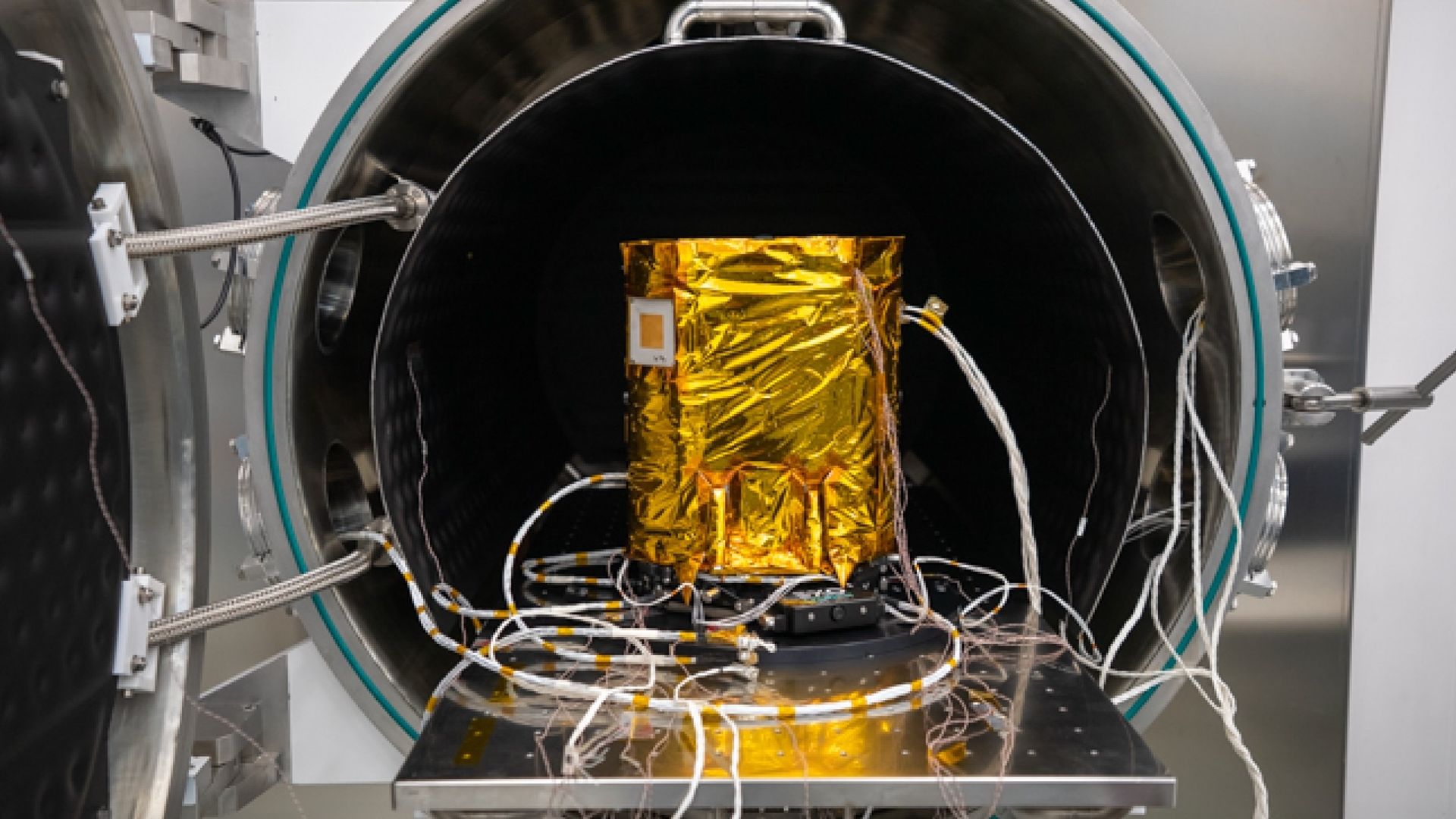 closeup of a rectangular golden spacecraft with lots of wires running from it