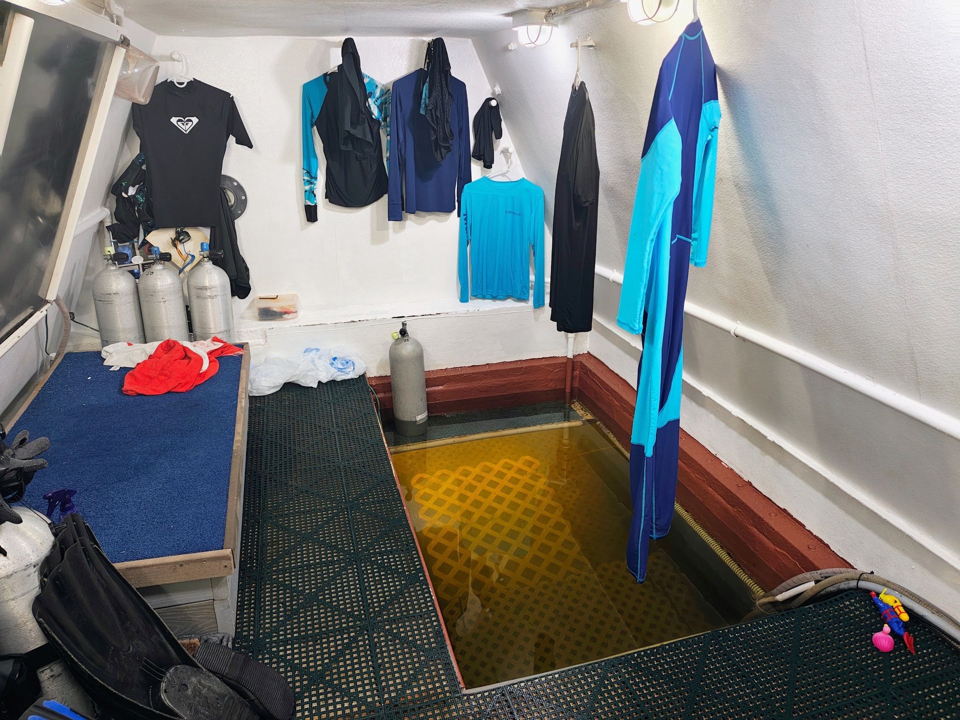photo inside a small room of a research station, showing wet suits and scuba gear arrayed along the walls